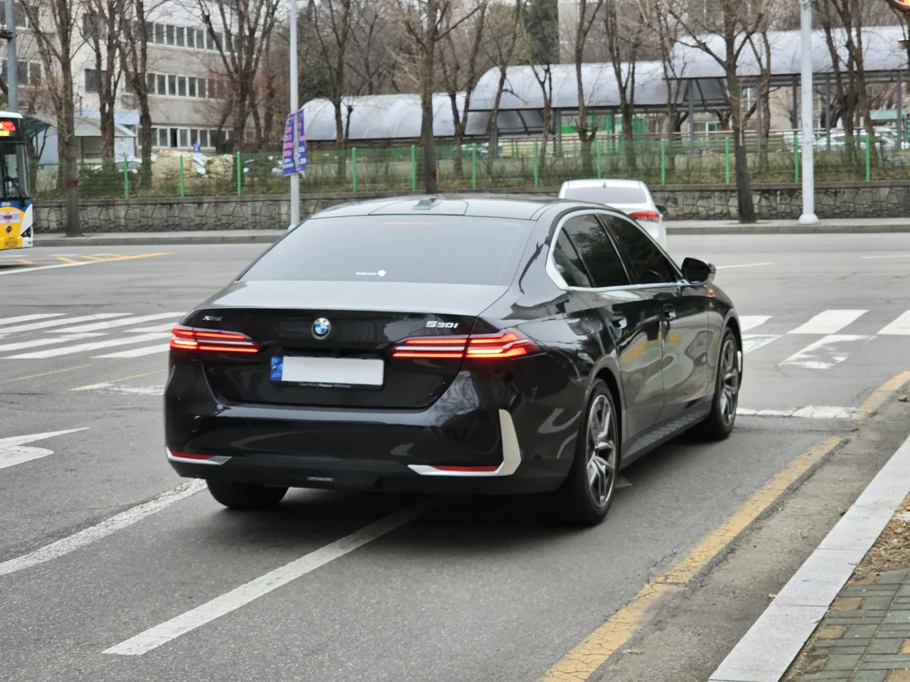 Black BMW 5 Series G60 sedan, full rear three-quarter view