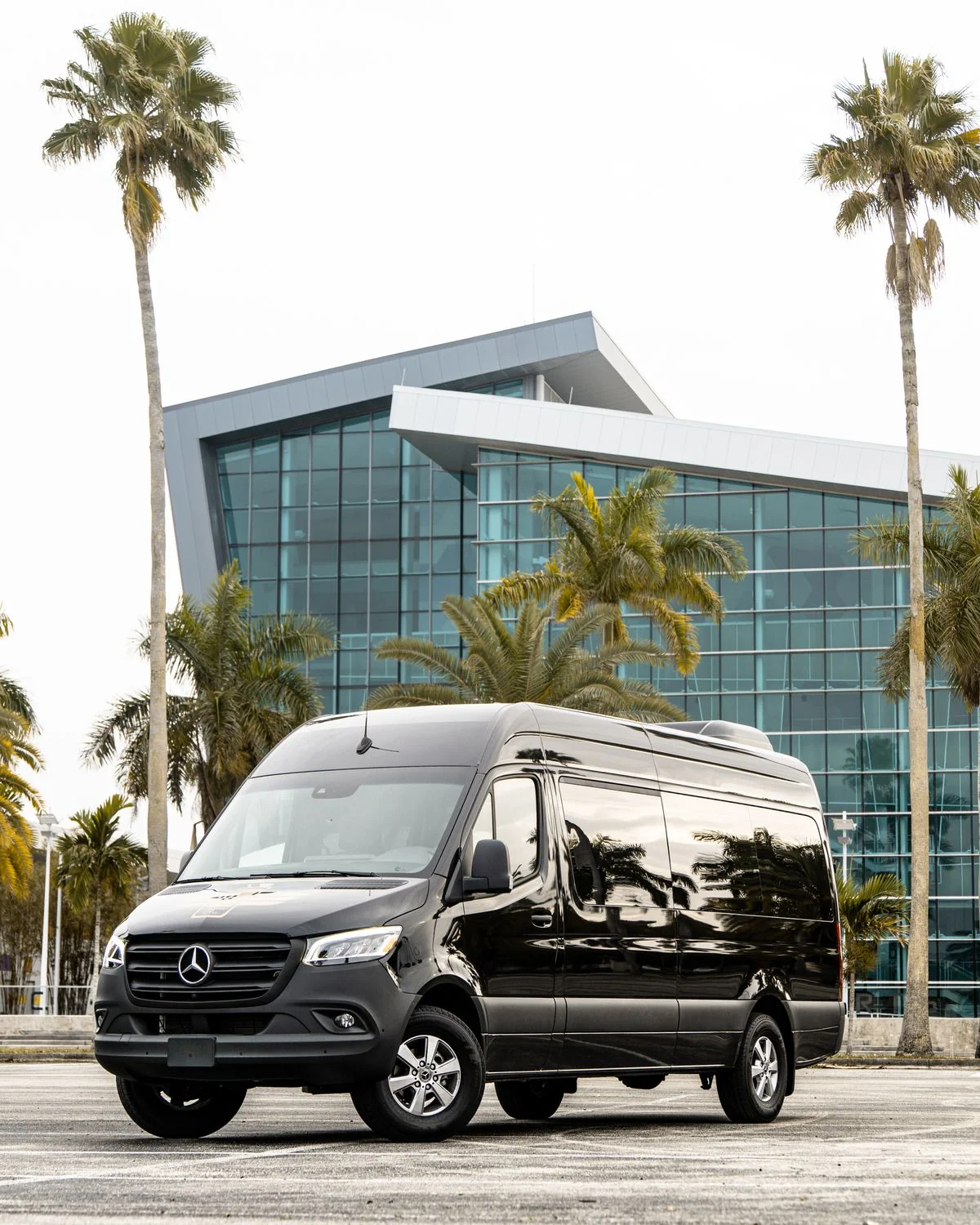 Black Mercedes-Benz Sprinter van parked beside a glass building